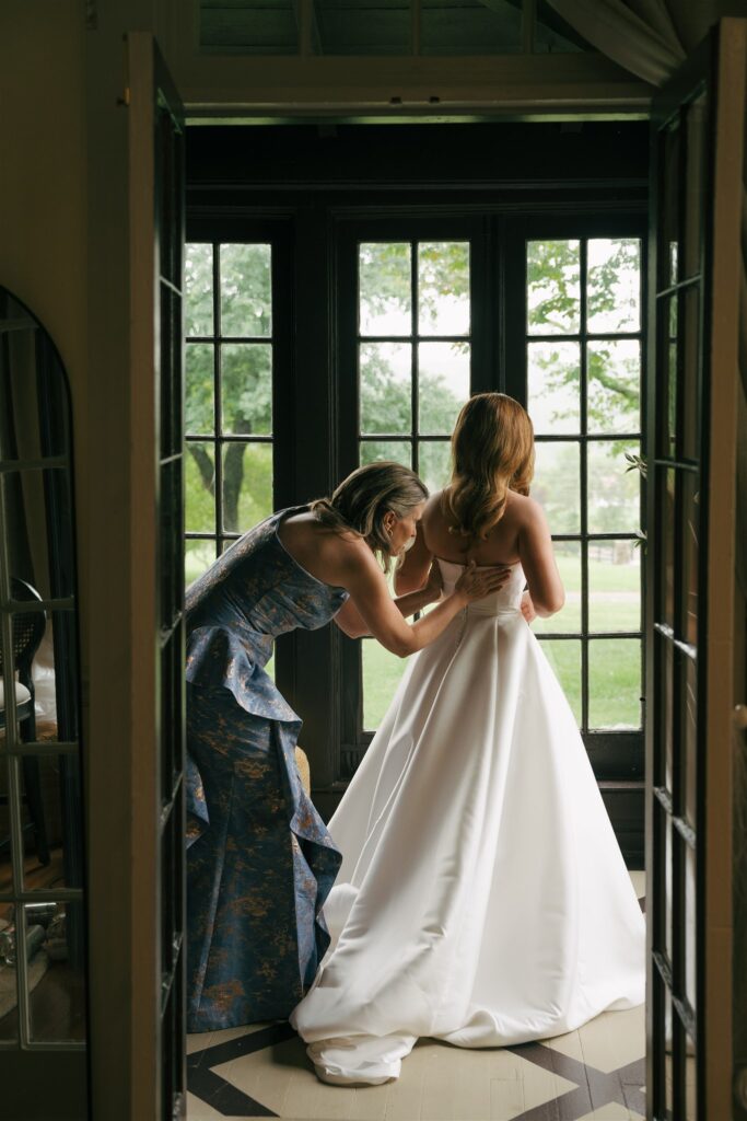 mother of the bride helping her with her wedding dress