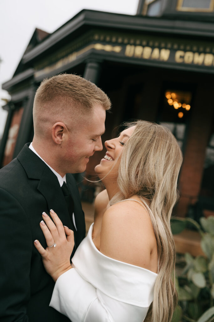 couple smiling at each other outside Nashville bar for engagement photos 