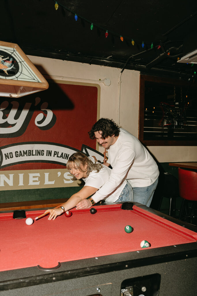 couple playing pool at a bar
