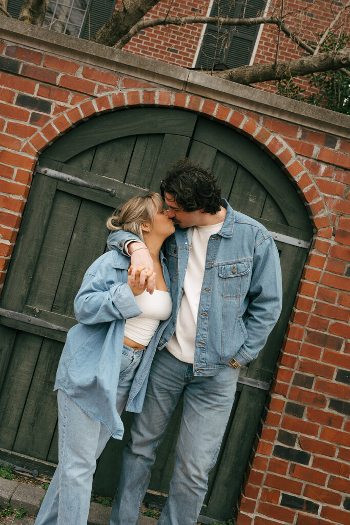 couple kissing in front of a gate