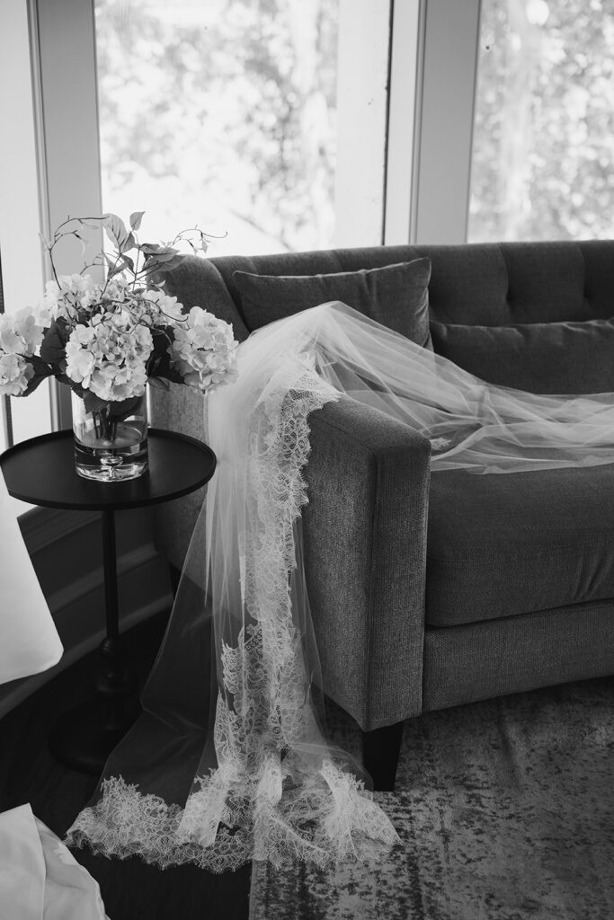 wedding veil laying on couch next to vase of flowers