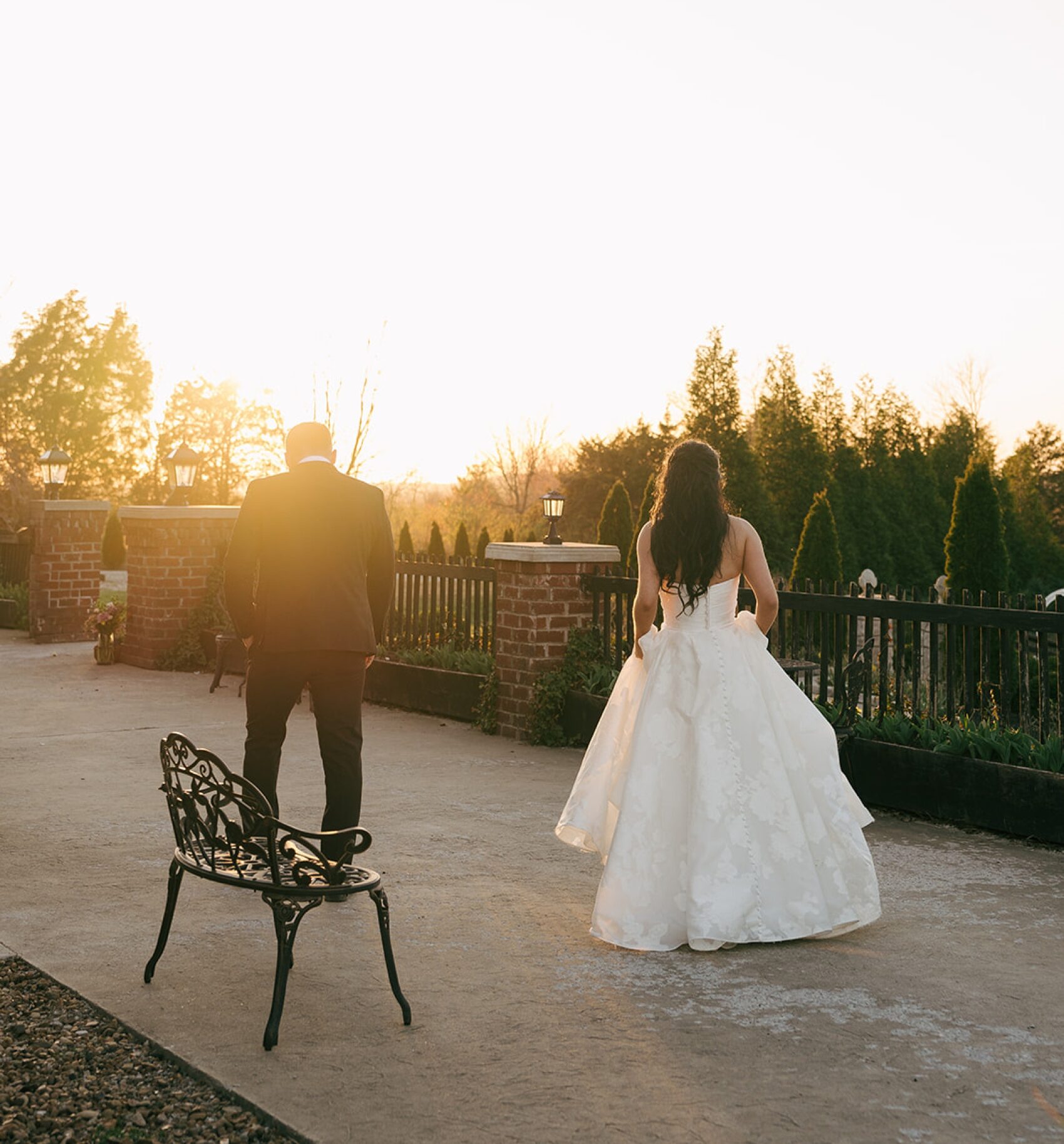 Newlyweds walk on the balcony admiring the sunset over the gardens