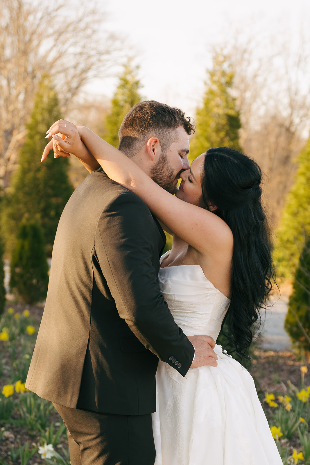A bride and groom embrace for a kiss in a flower garden at sunset during their Nashville destination wedding