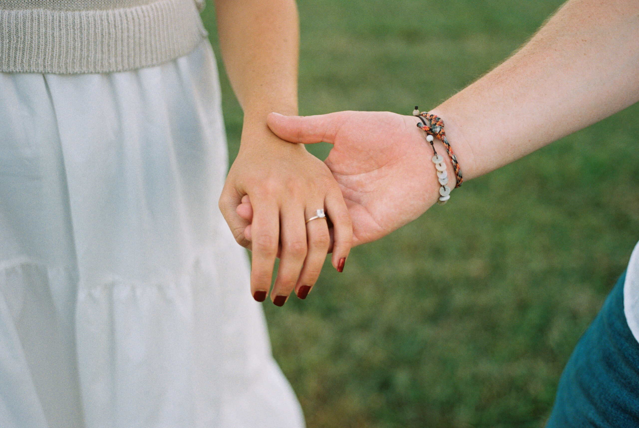 Man holding woman's hand to show engagement ring on film photographed in Nashville, Tennessee
