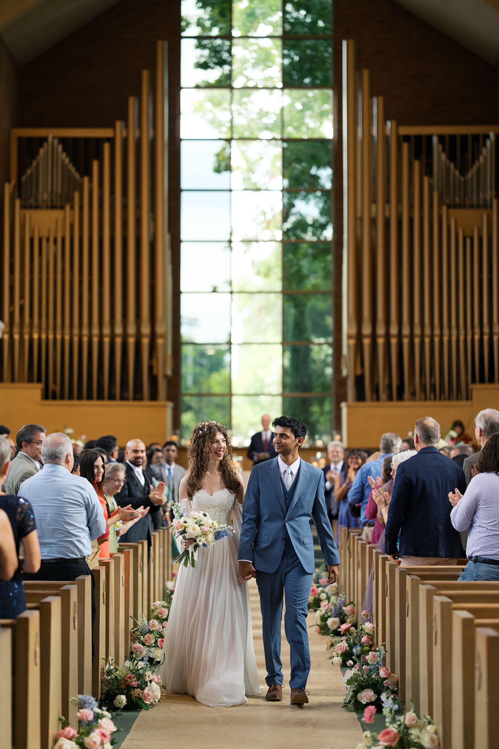 Newlyweds exit up the vine street christian church wedding venue aisle as guests applaud them