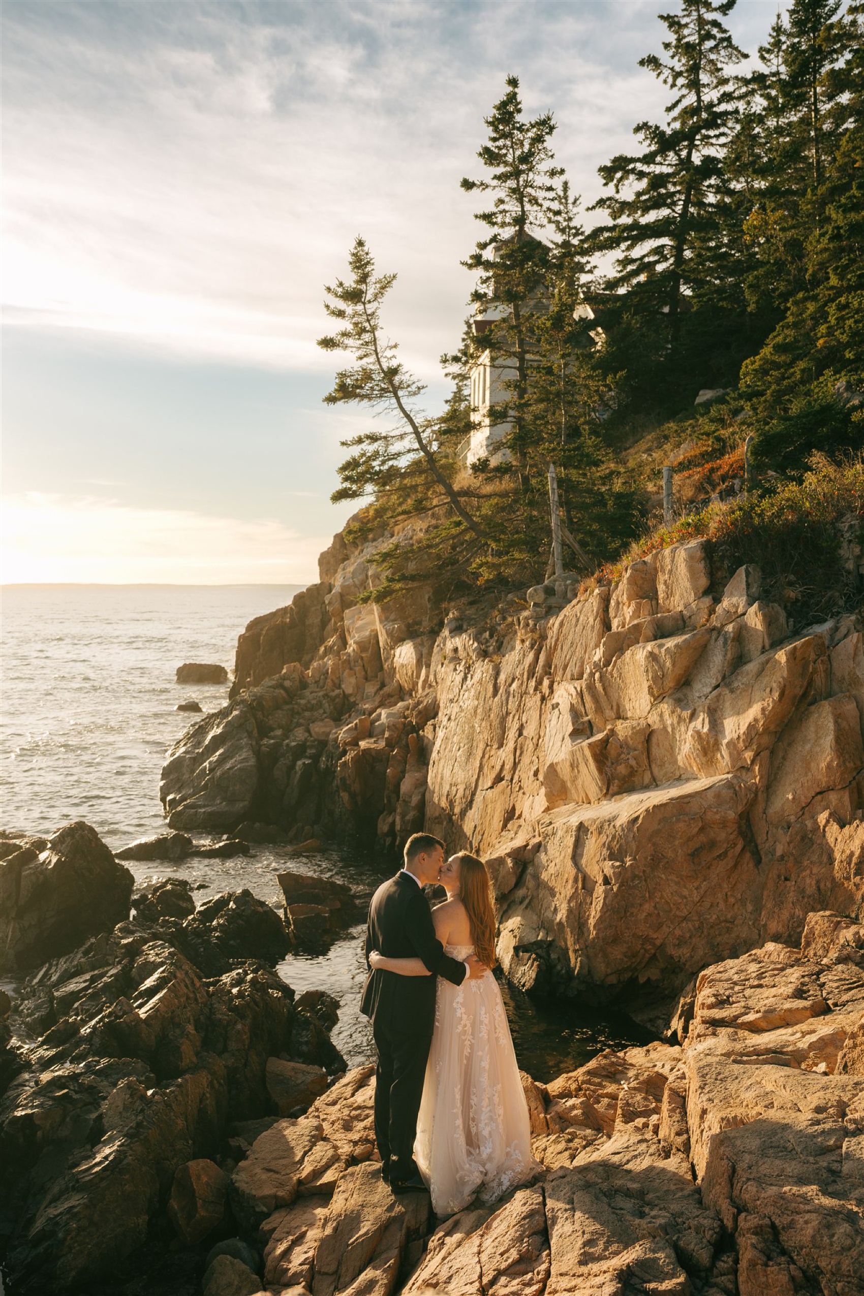 A bride and groom kiss on a rocky embankment at sunset during their Acadia National Park Elopement