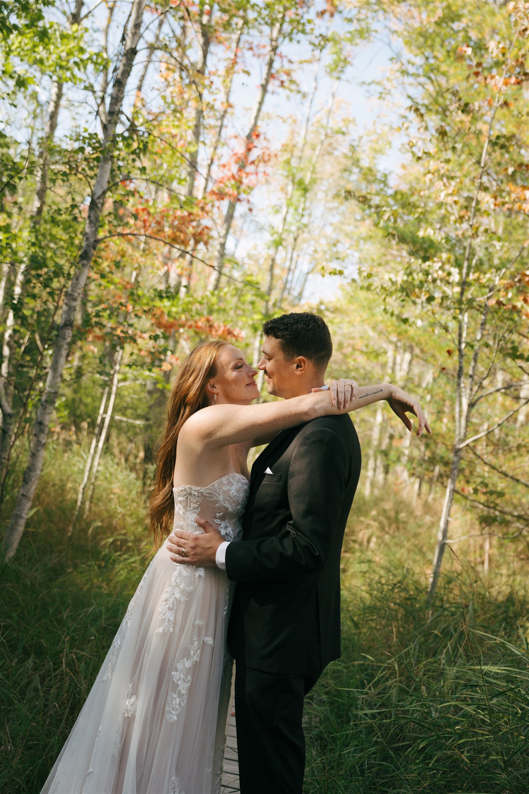 Newlyweds share a quiet moment with arms around each other in the forest during their Acadia National Park Elopement