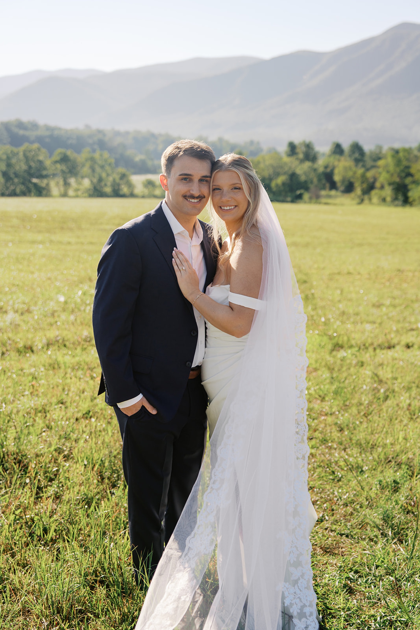 Newlyweds snuggle chest to chest in a large open meadow in the Smokies