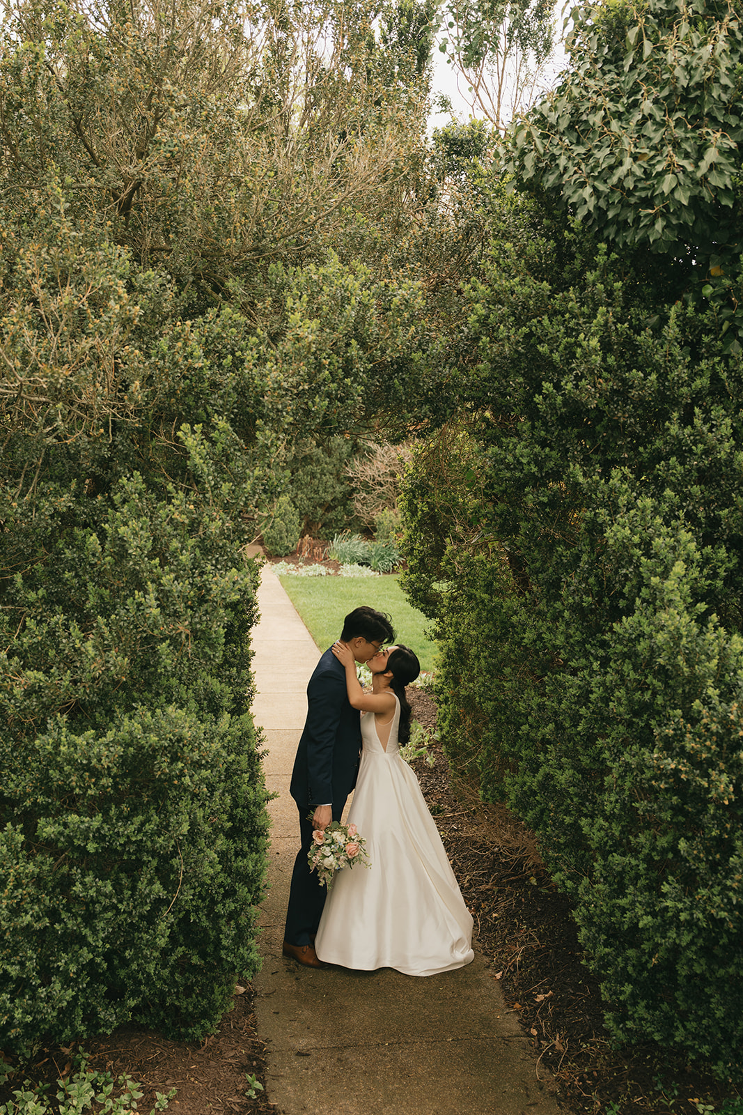 Newlyweds kiss in a garden under a natural bush arch at one of the outdoor wedding venues in Nashville