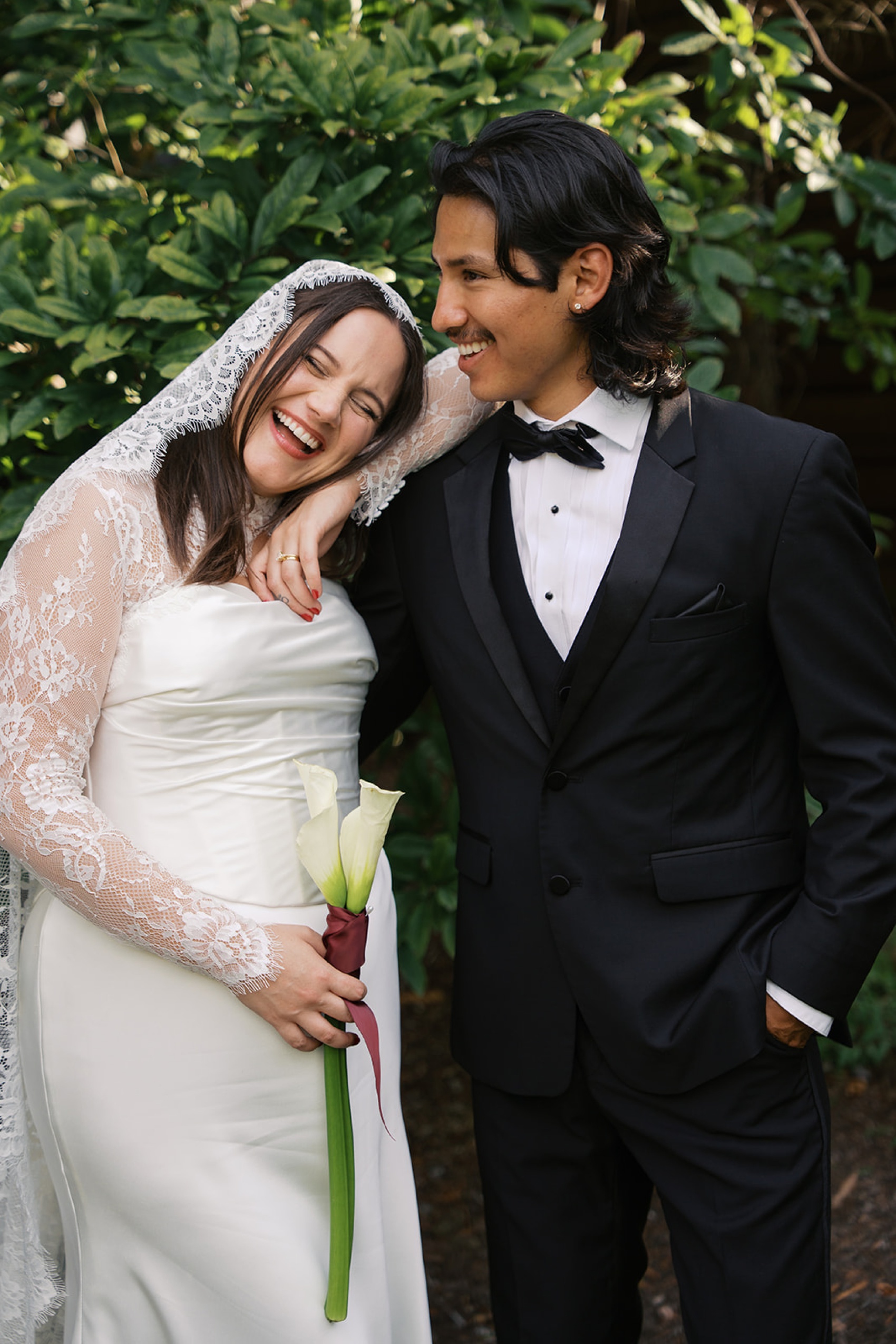 A bride laughs while leaning on her happy groom in the garden at the cordelle nashville