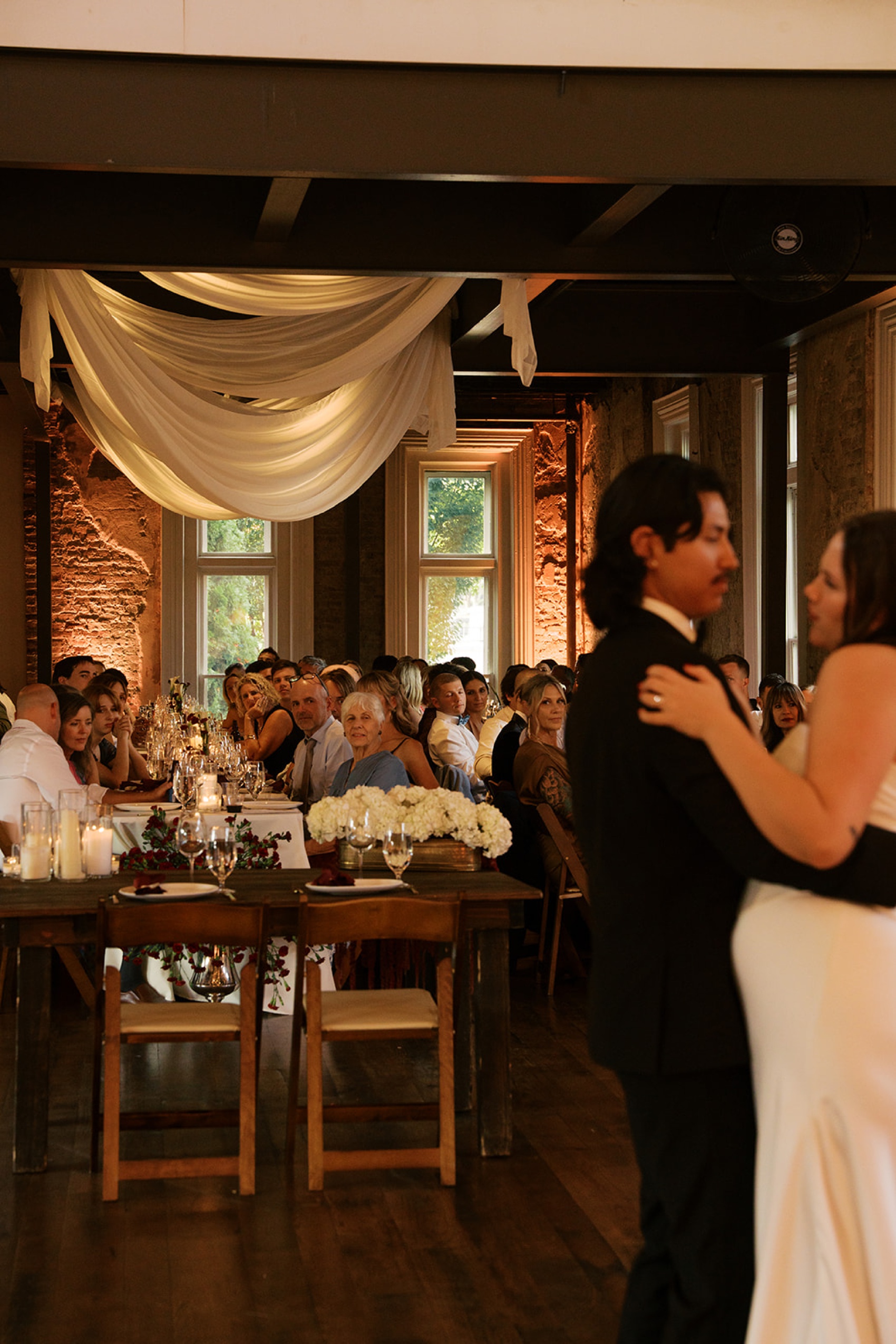 Newlyweds dance as guests look on from reception tables