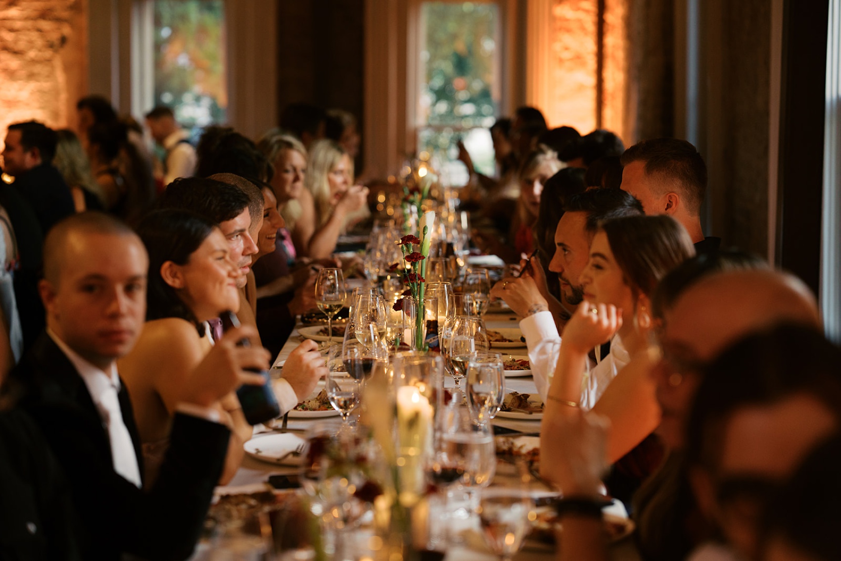 A look down a long wedding reception table as people laugh and eat at the cordelle nashville