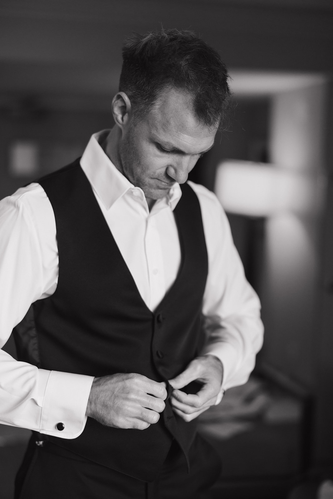 A groom buttons his vest in black and white during his The Hermitage Hotel wedding