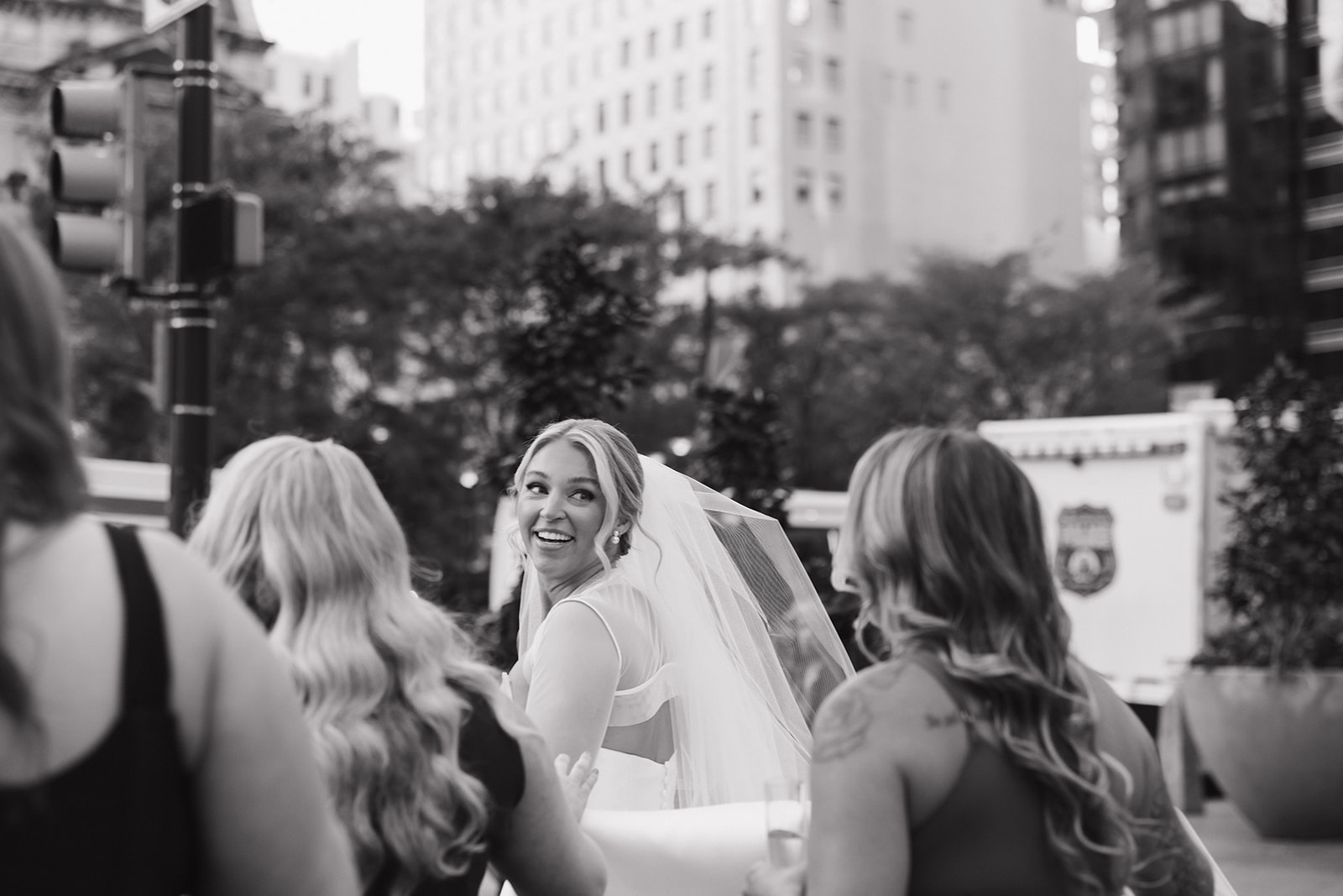 A bride laughs while walking downtown with her bridesmaids at her The Hermitage Hotel wedding