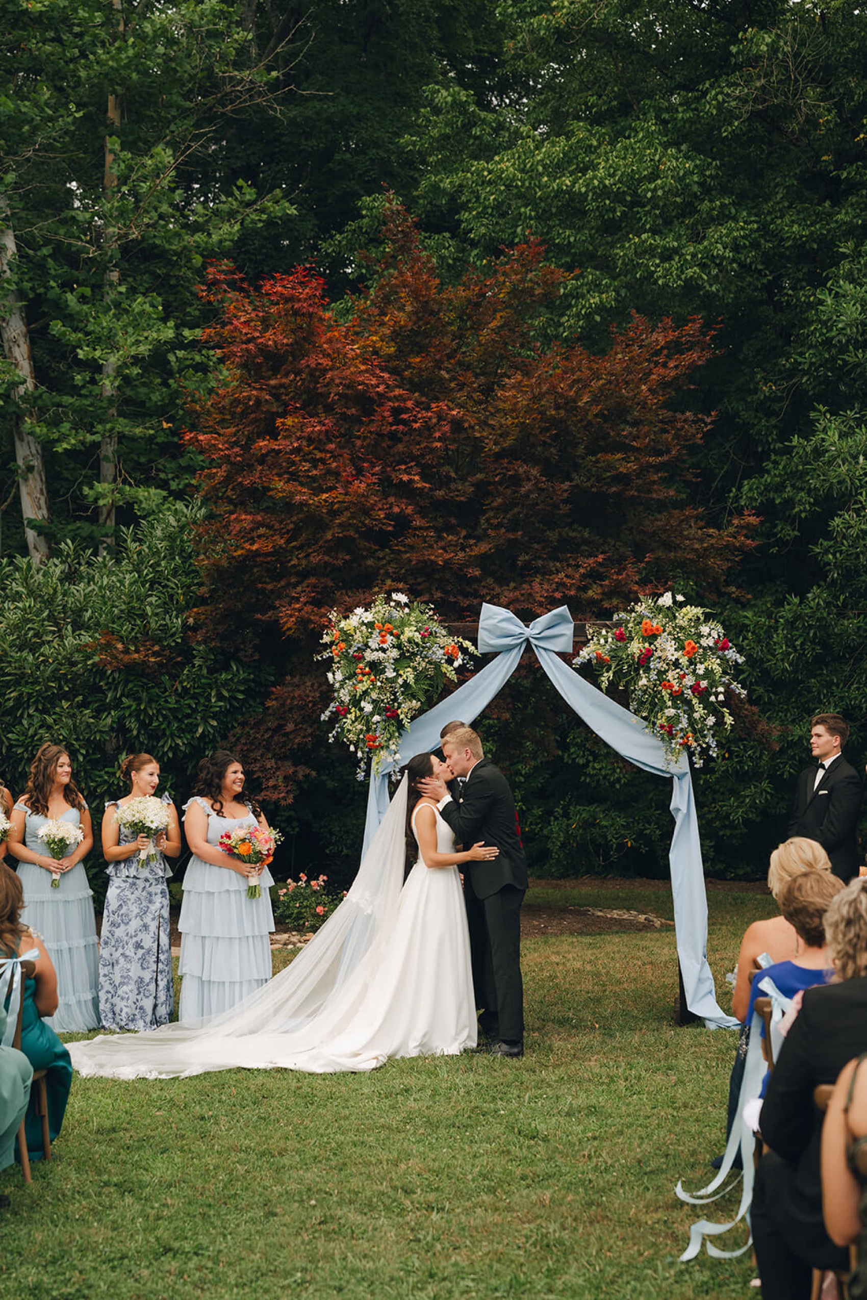 a groom kisses his bride to end their outdoor garden wedding ceremony
