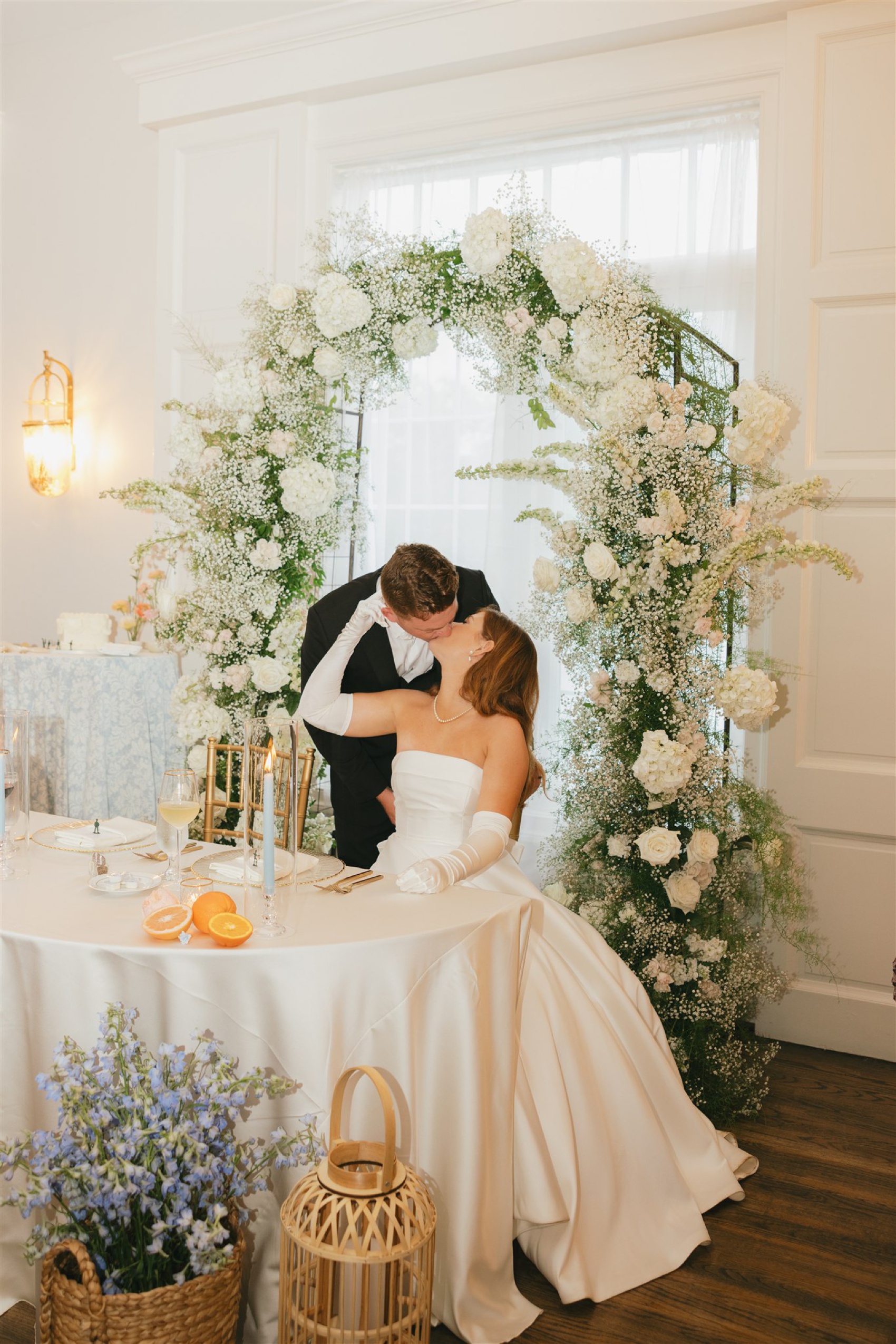 newlyweds kiss at the head table with a white flower arch during their Black Horse Manor wedding reception