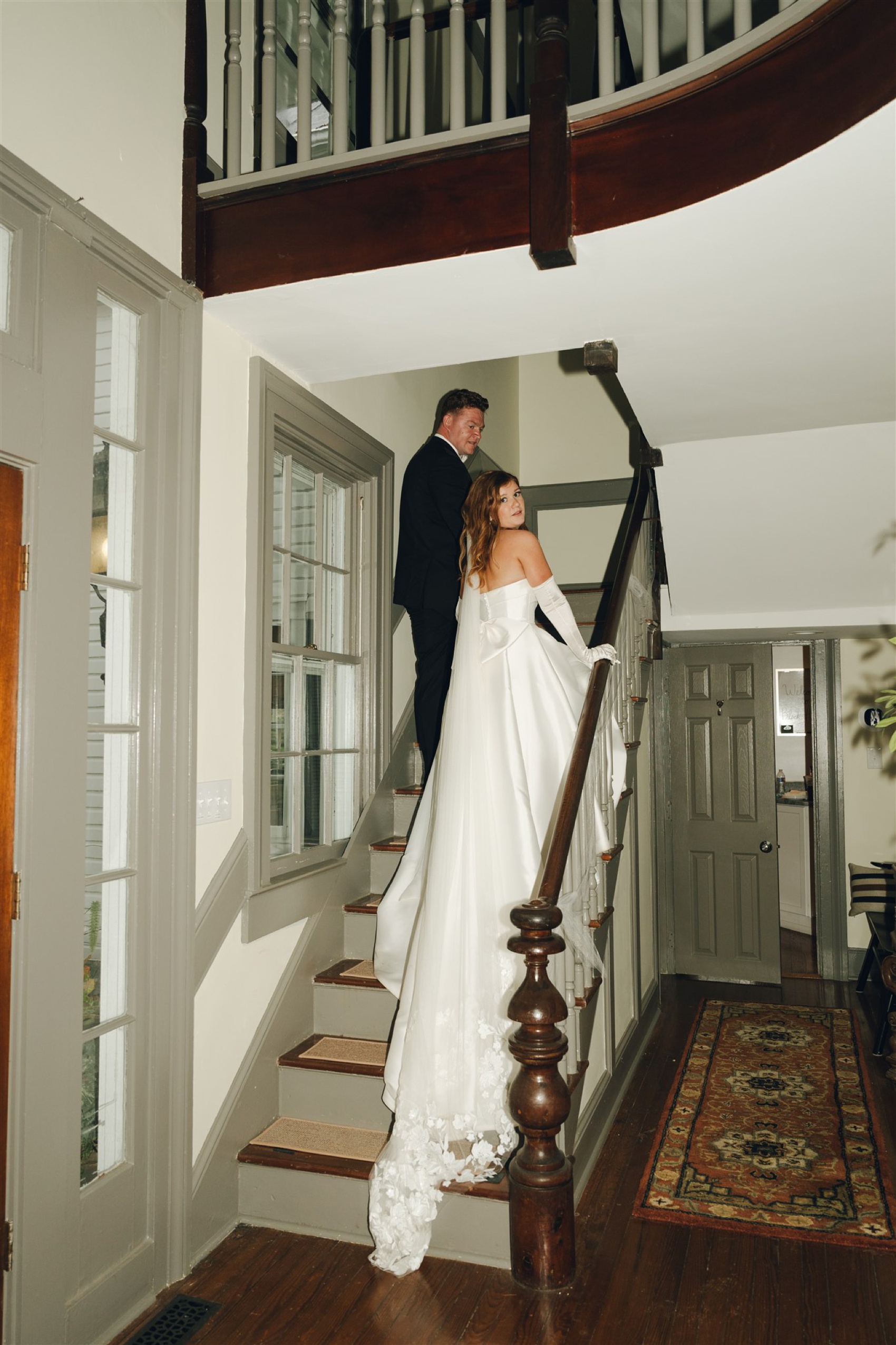 a groom leads his bride up the stairs of the Black Horse Manor as she looks back over her shoulder