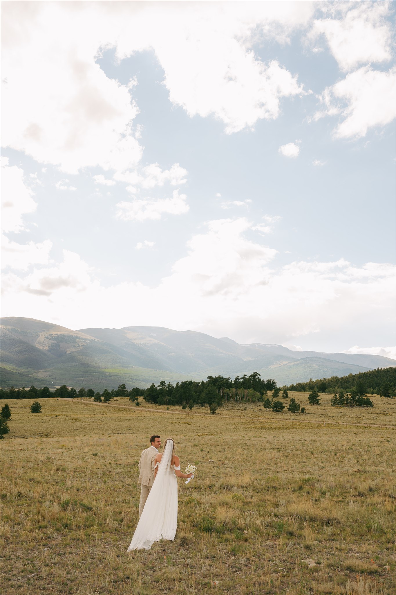 newlyweds take a stroll in a pasture at sunset with epic views thanks to their Nashville wedding planners