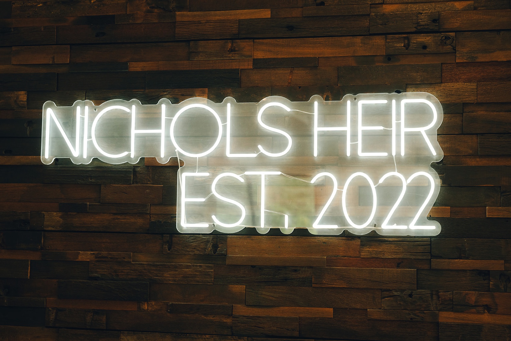 Details of a nichols heir wedding venue neon sign on a wooden wall