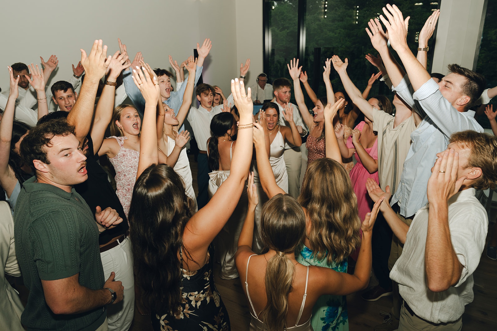A bride dances and screams with hands up with a hord of wedding guests on the dance floor