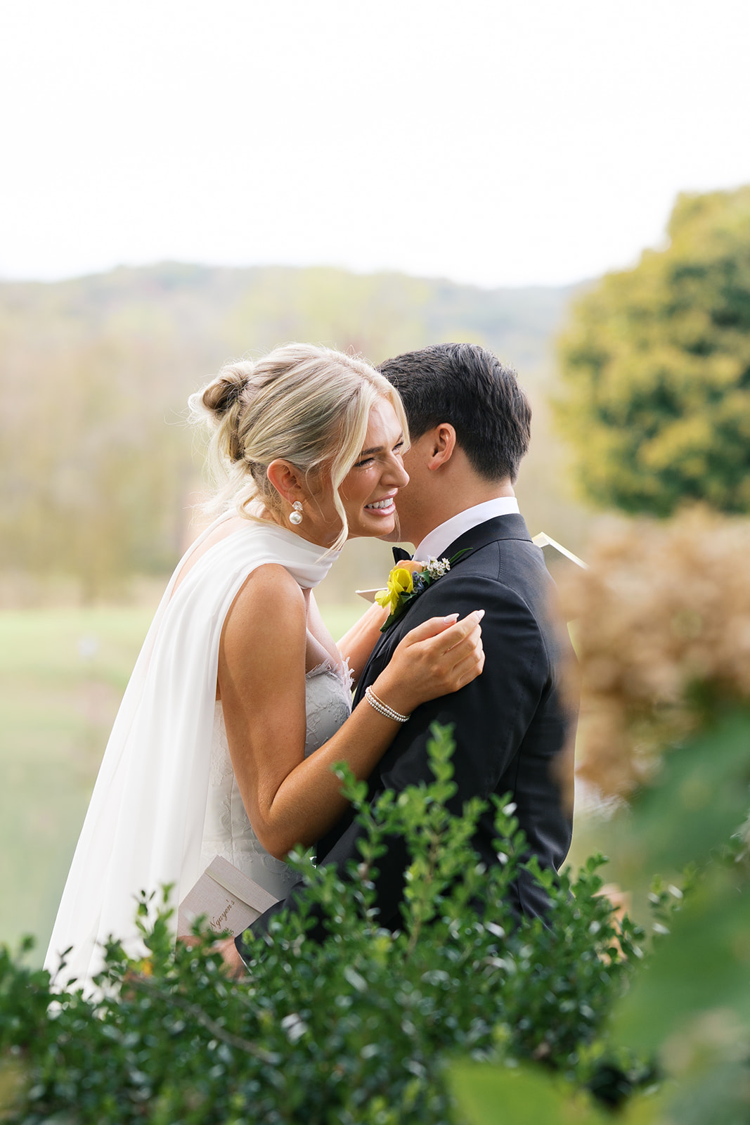 a bride giggles while coming in the hug her groom in a garden