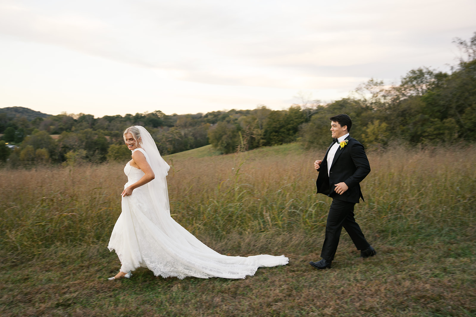 Newlyweds walk in a meadow in the mountains during their Blackberry Farm wedding at sunset