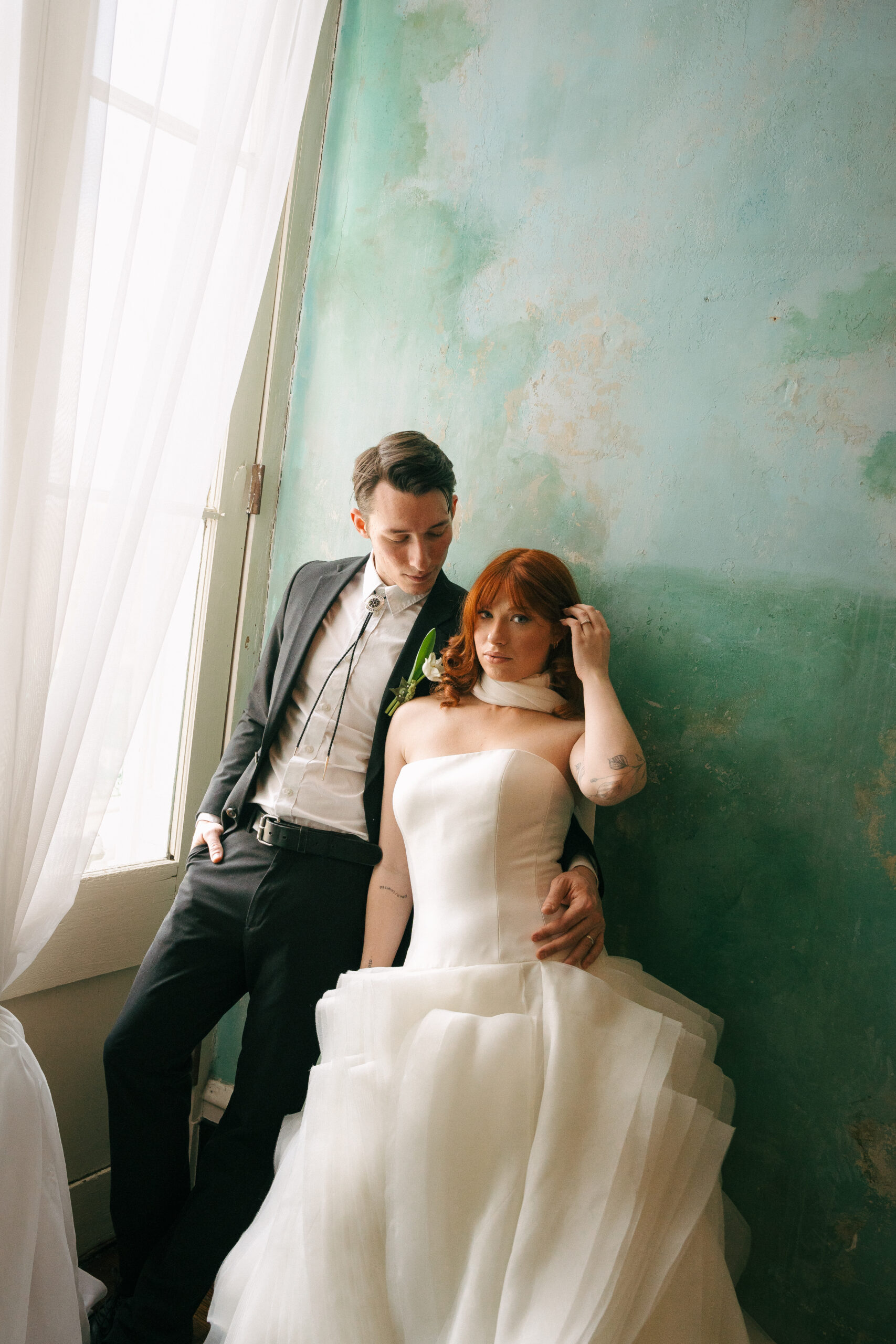 A bride and a groom holding onto each other at a wedding venue in tennessee with a blue wall.