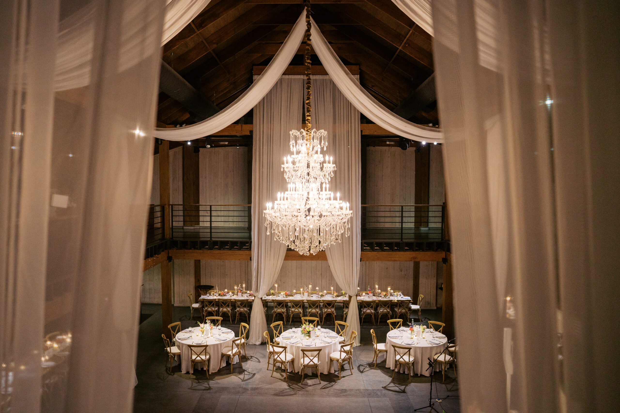 A beautiful ballroom styled with white curtains and low lighting at mint springs farm wedding venue
