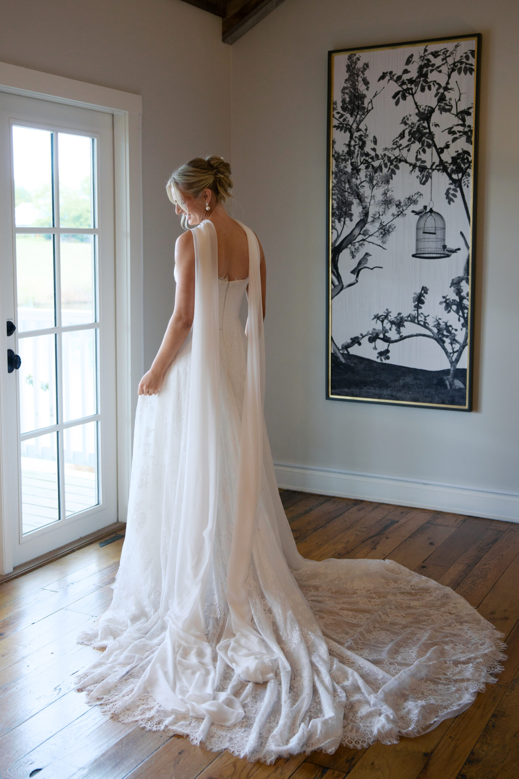 A bride looking out the window in her wedding dress with a scarf at mint springs farm