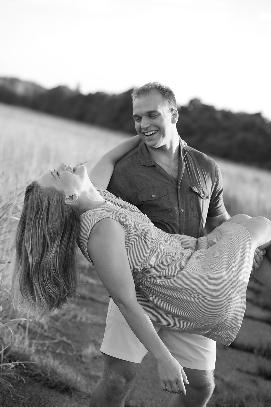 a man holding a woman laughing during their engagement session at cornelia fort airpark in nashville