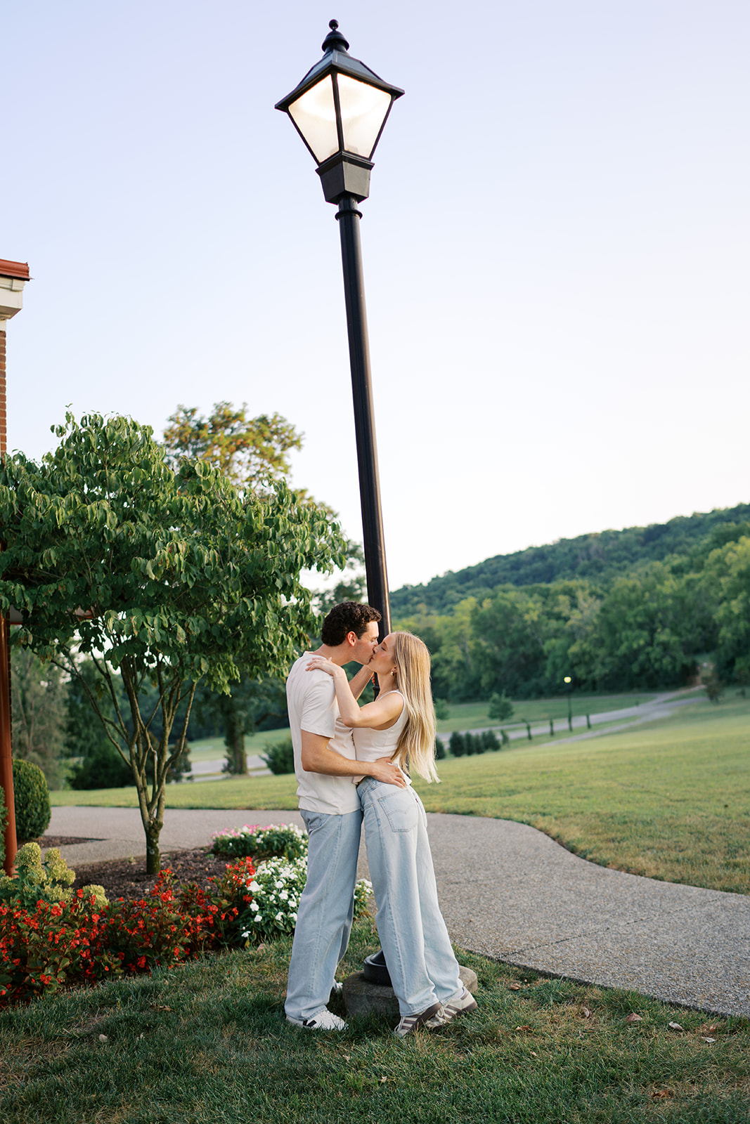 couple holding onto a light post kissing wearing jeans and white t shirts