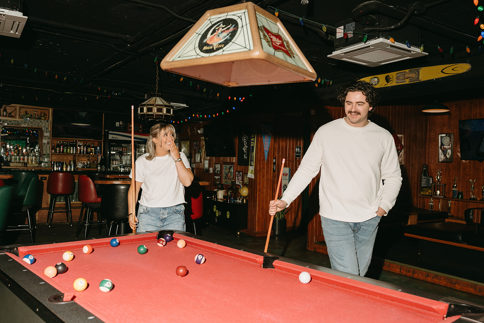 couple playing pool laughing at luckys bar in nashville during their engagement photos