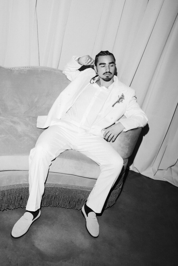 a groom in black and white leaned up against a fancy couch at his wedding at diamond creek farms in nashville
