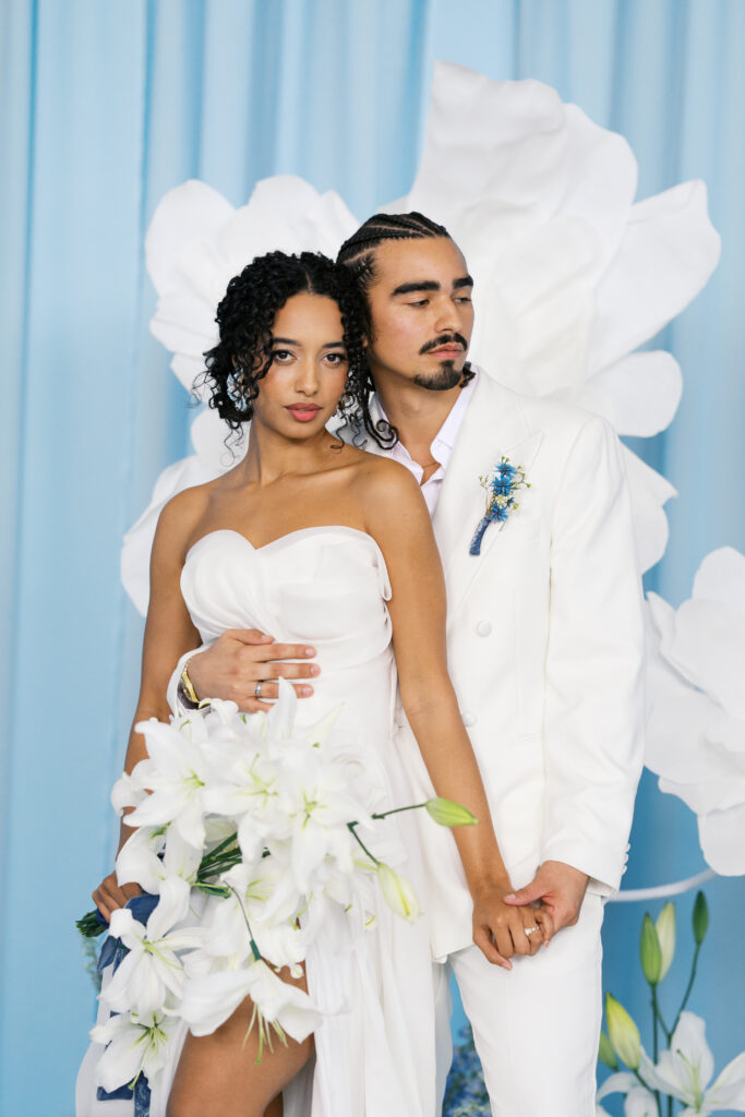 A couple in white holding hands standing in front of blue draping at a wedding at diamond creek farms in nashville tennessee.