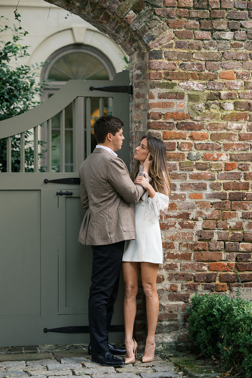 A couple looking at each other on a brick wall in charleston south carolina.