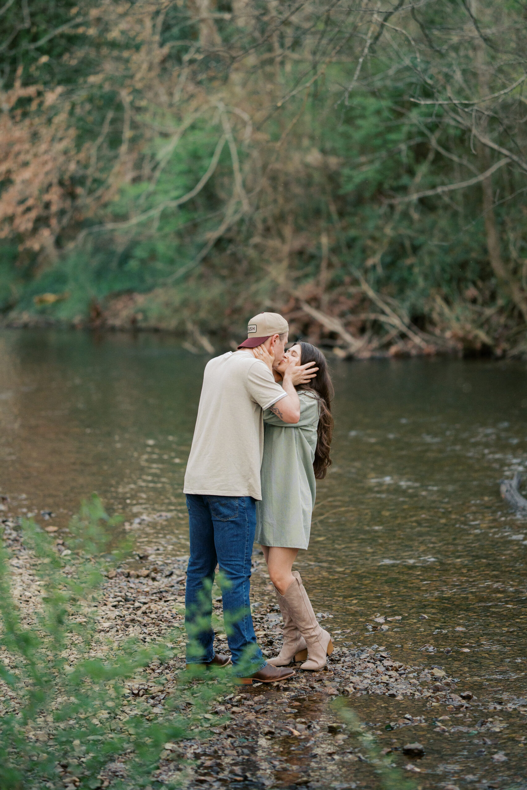 A couple standing in the creek at their leipers fork engagement session in tennessee kissing.