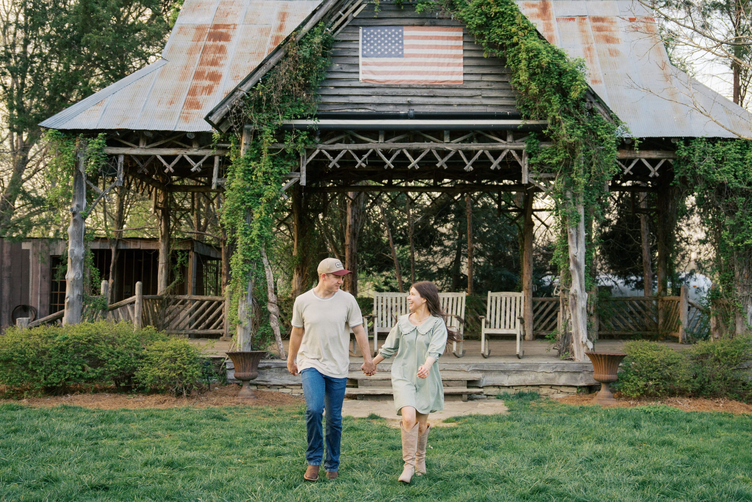 A couple holding hands running away from a pavilion at their leipers fork engagement session