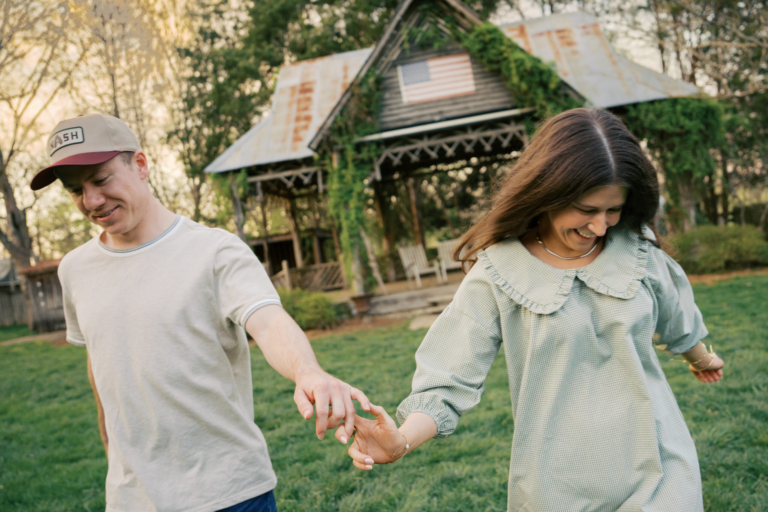 A couple holding hands laughing and running into the camera during their engagement session.