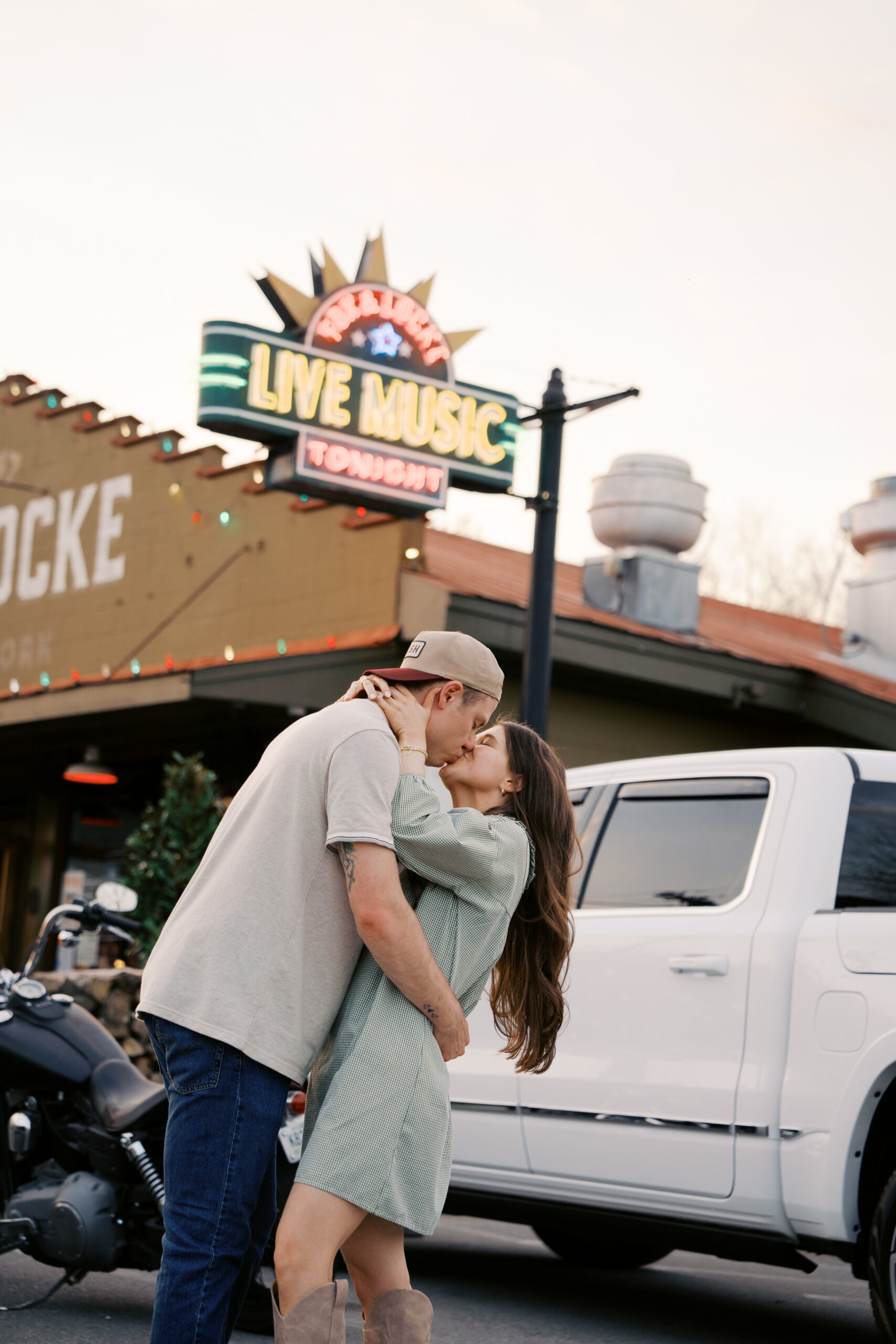 A couple under the fox and locke sign in leipers fork kissing during their engagement session.