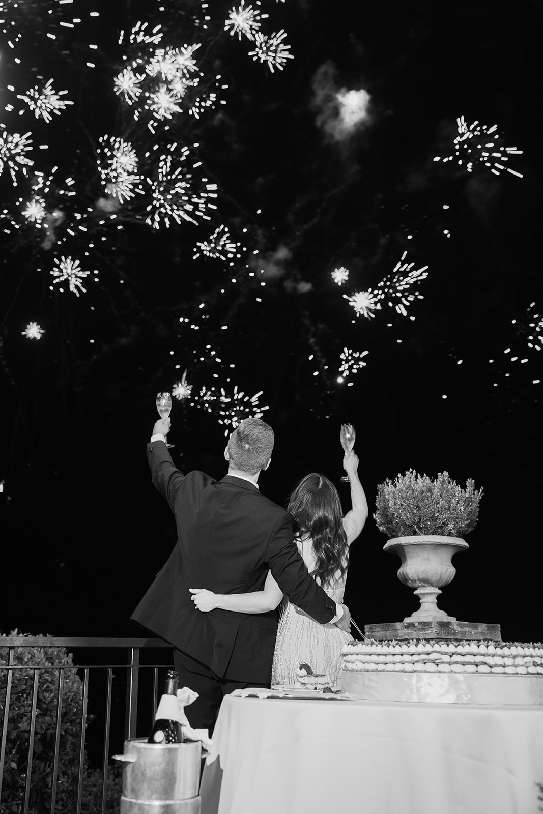 A couple points up to the sky at fireworks during their destination wedding in italy