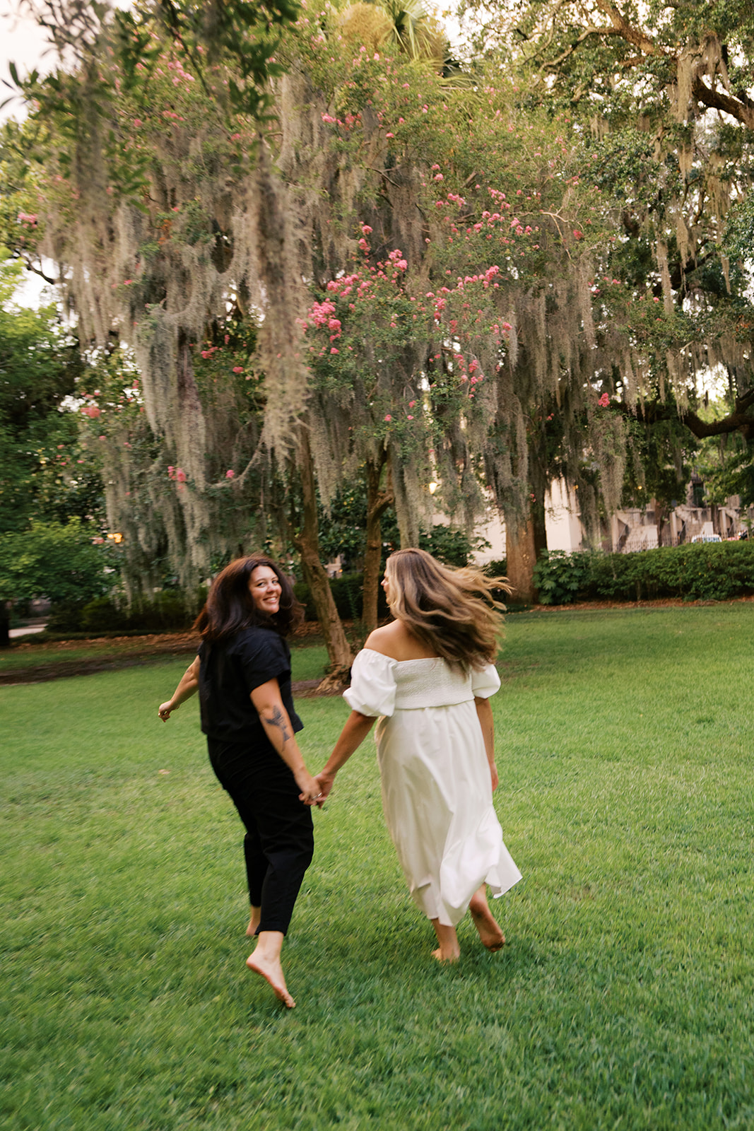two girls holding hands in forsyth park savannah georgia during their engagement session