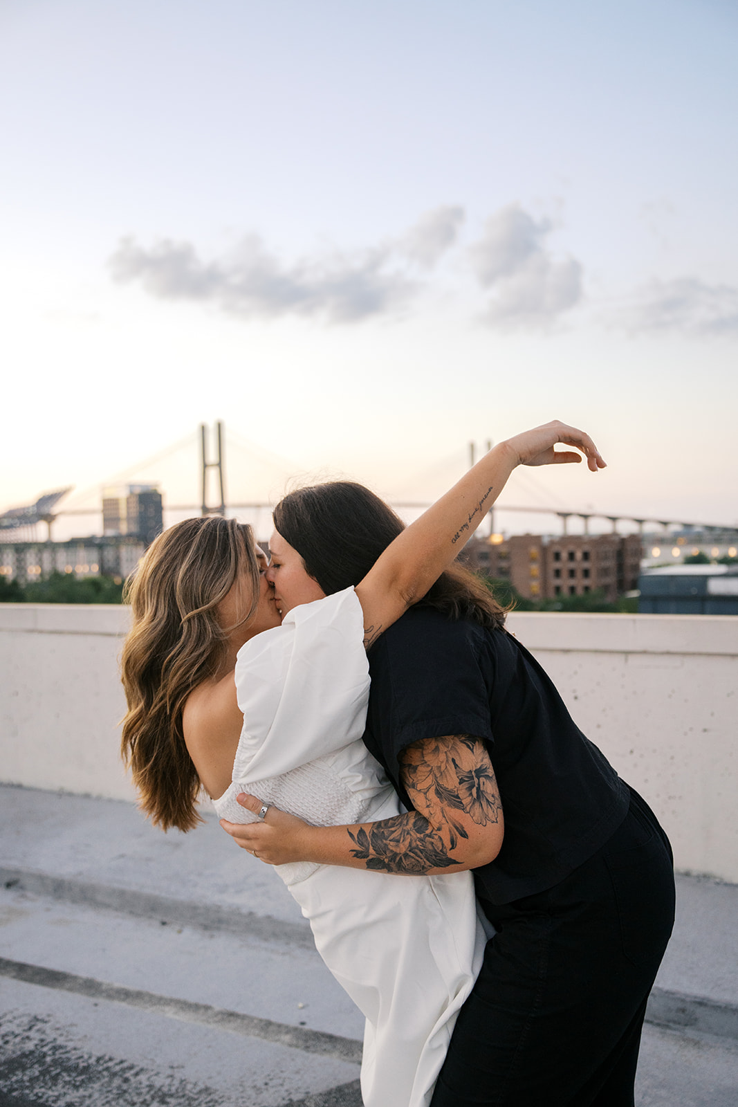 two brides kissing on a rooftop with a sunset in savannah georgia 