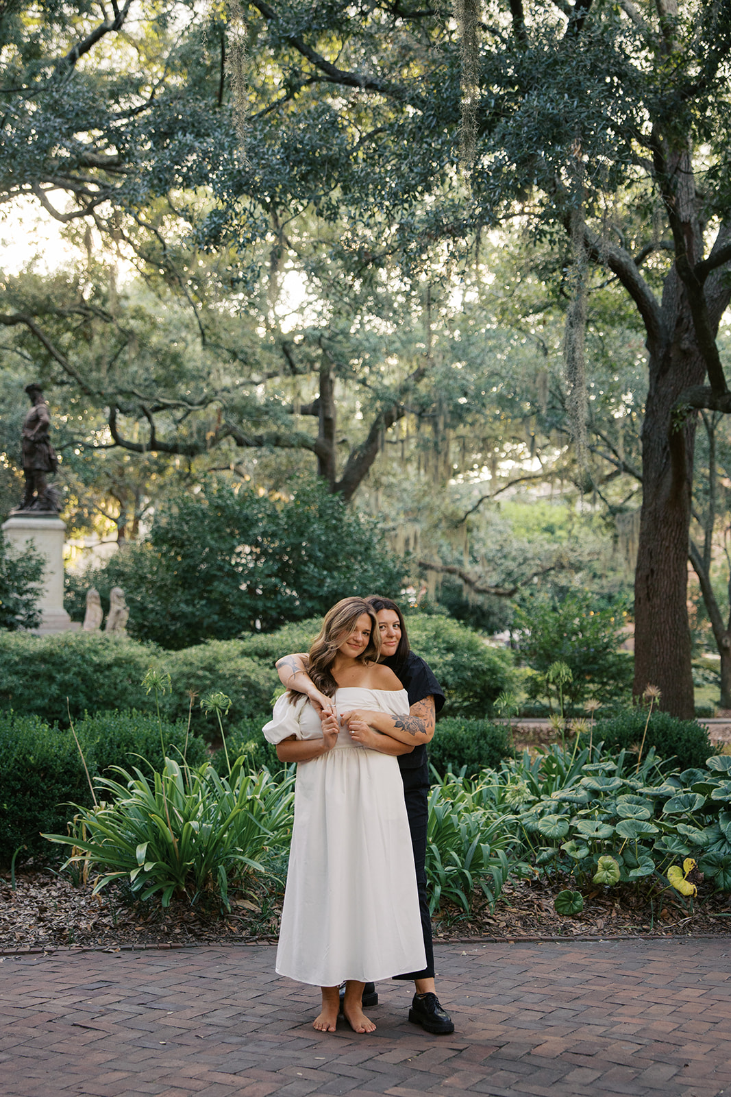 Two girls holding each other from behind looking at the camera during their engagement session in savannah georgia. 