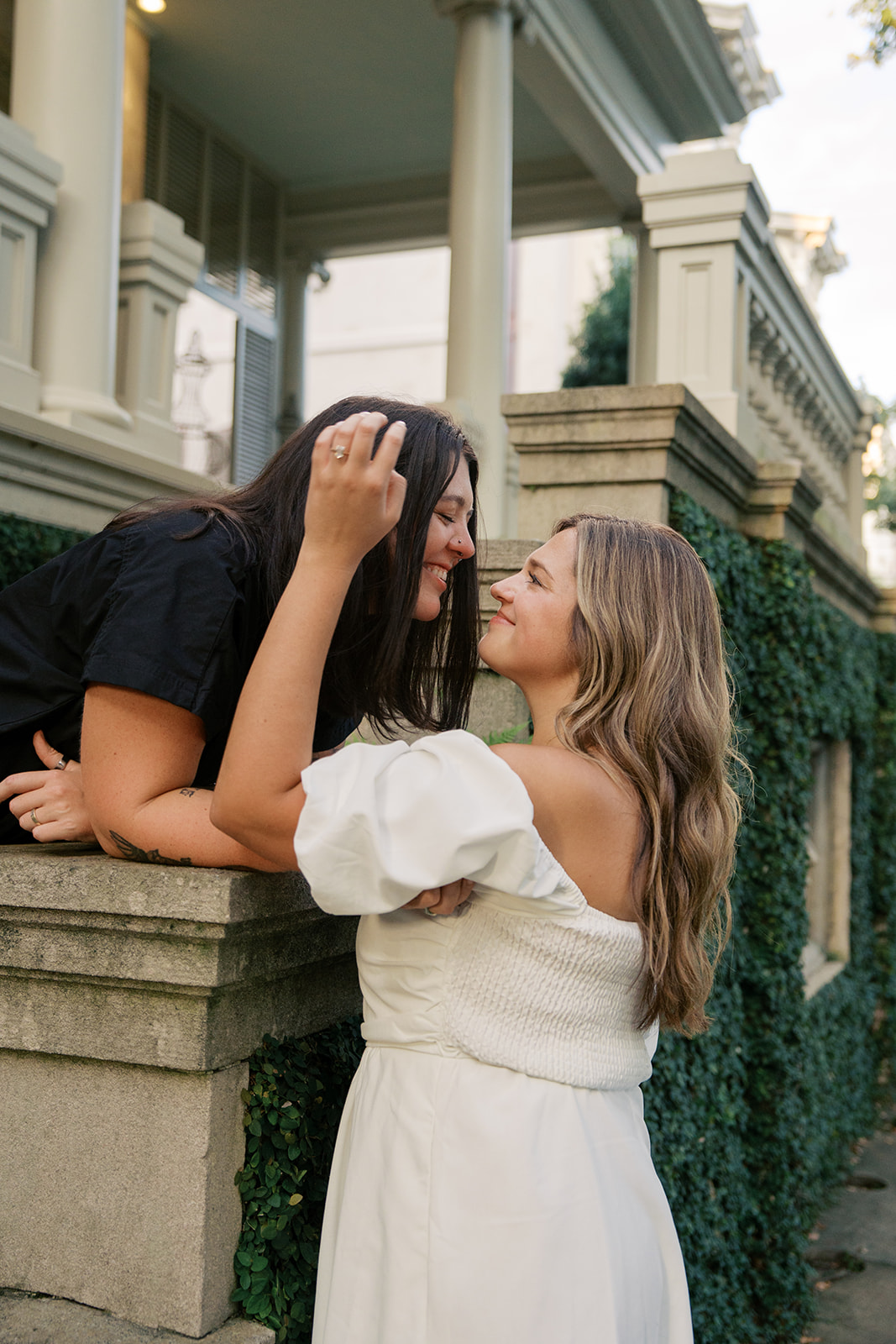 Two girls give each other a kiss over a stone house during their engagement session in savannah georgia