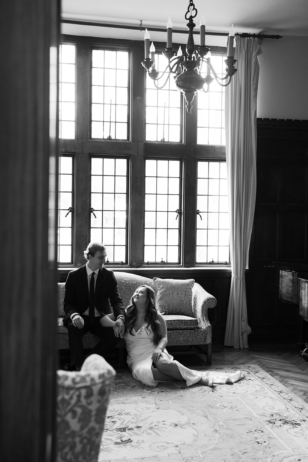 A bride sits on the floor in front of a couch while the groom reaches down and touches her hand at scarritt bennett center.