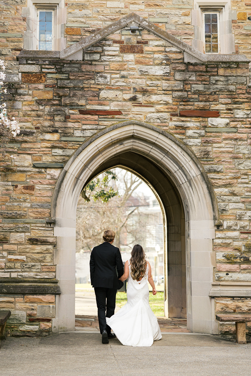 A bride and groom hold hands and walk between an arch at scarritt bennett center photographed by jaimee raneigh photography.