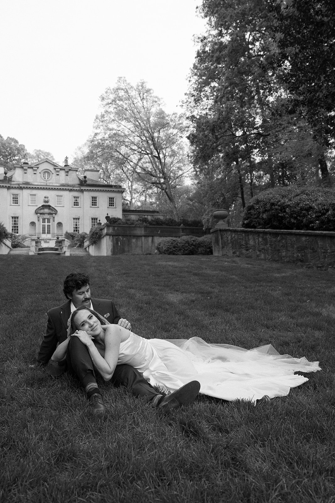 A couple sitting in front of the swan house after their wedding