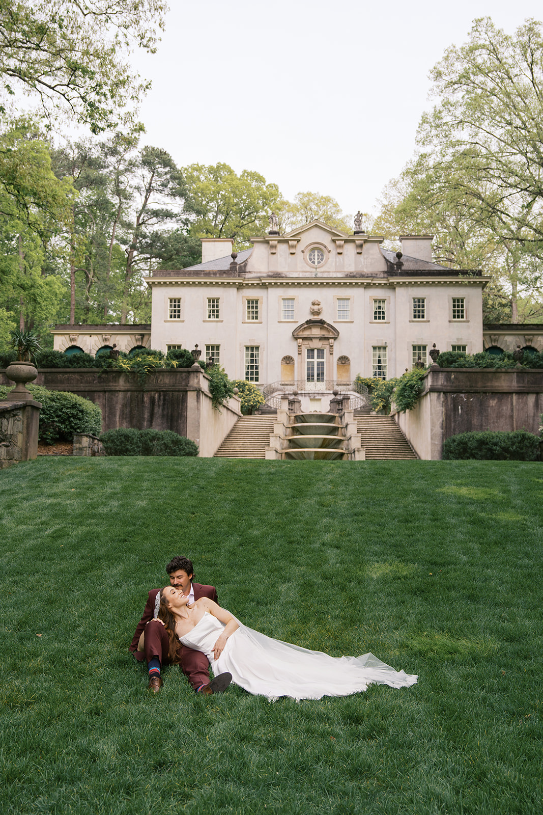 A couple laying down in the front lawn of the Swan House wedding venue. Photography by Jaimee Raneigh Photography.