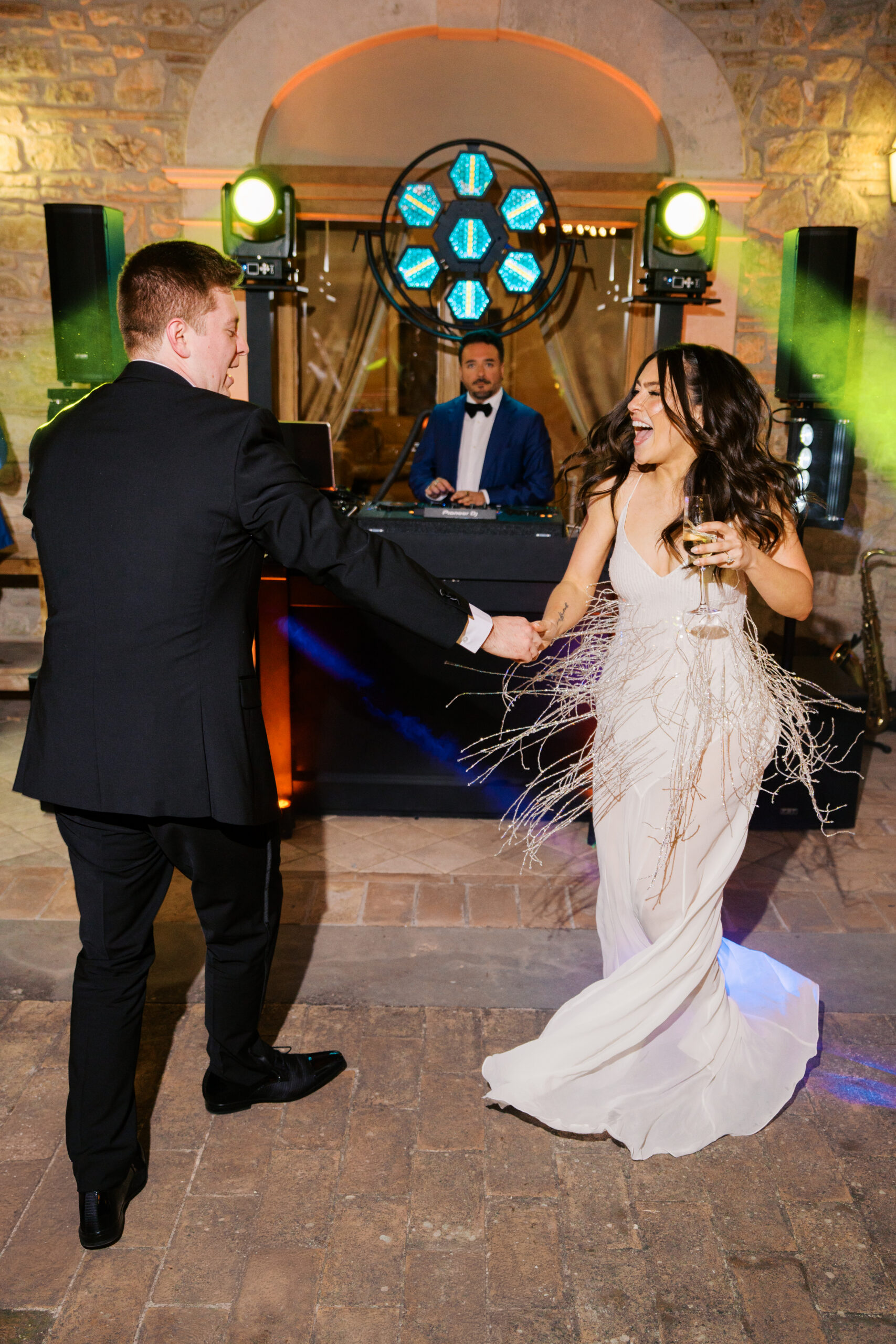 a bride and groom holding hands dancing in umbria italy during their wedding with neon lights in the background 