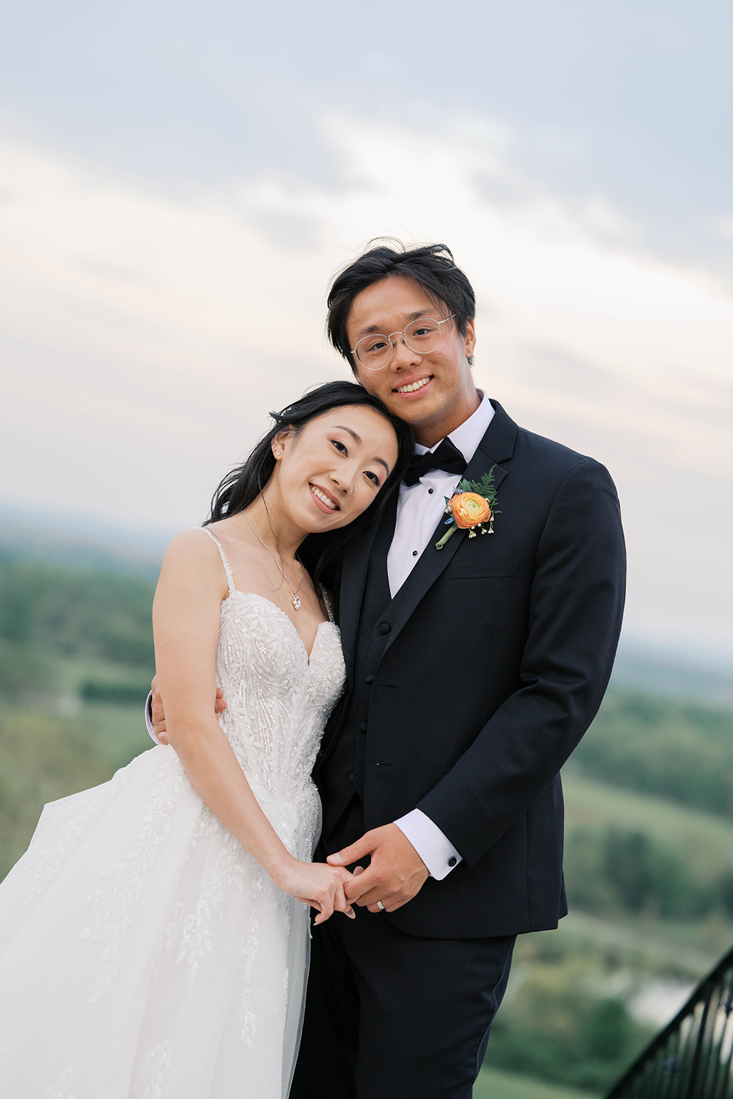 A sunset portrait of a bridal couple looking at the camera and holding hands at the view at bluemont wedding venue in virginia.